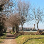 Ciclista sul sentiero sterrato del Percorso Nero Franciacorta verso l'Abbazia di San Nicola a Rodengo Saiano.