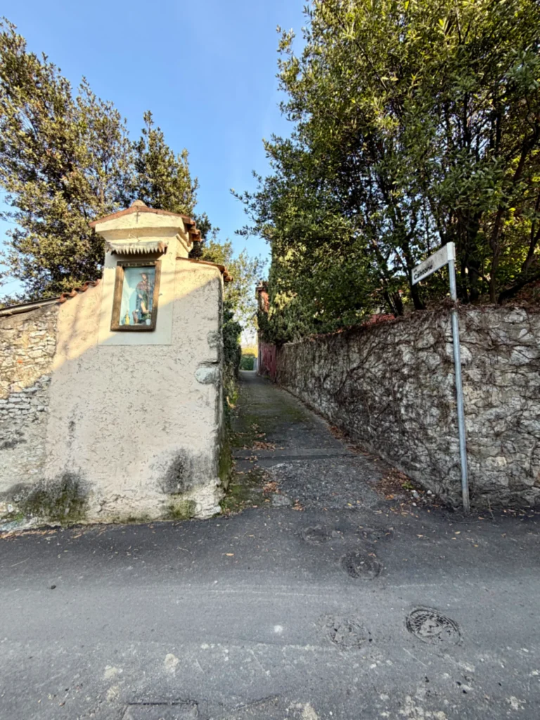 via-cantone-cellatica-franciacortino.jpg Un vicolo stretto tra mura in pietra a Cellatica con un'edicola votiva di San Rocco a sinistra e il cartello stradale di Via Cantone a destra.